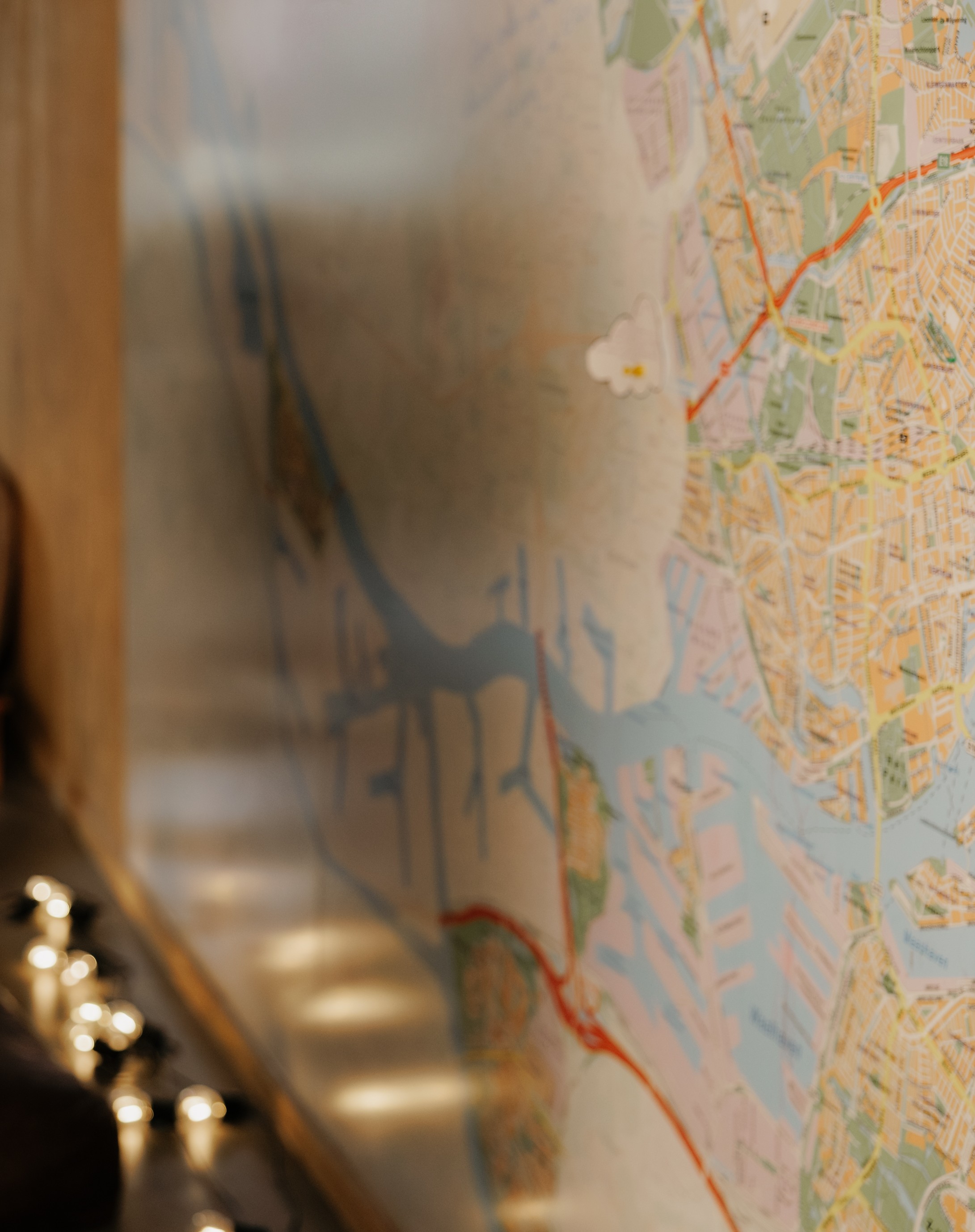A city map pinned to a wall with bokeh lights in the foreground